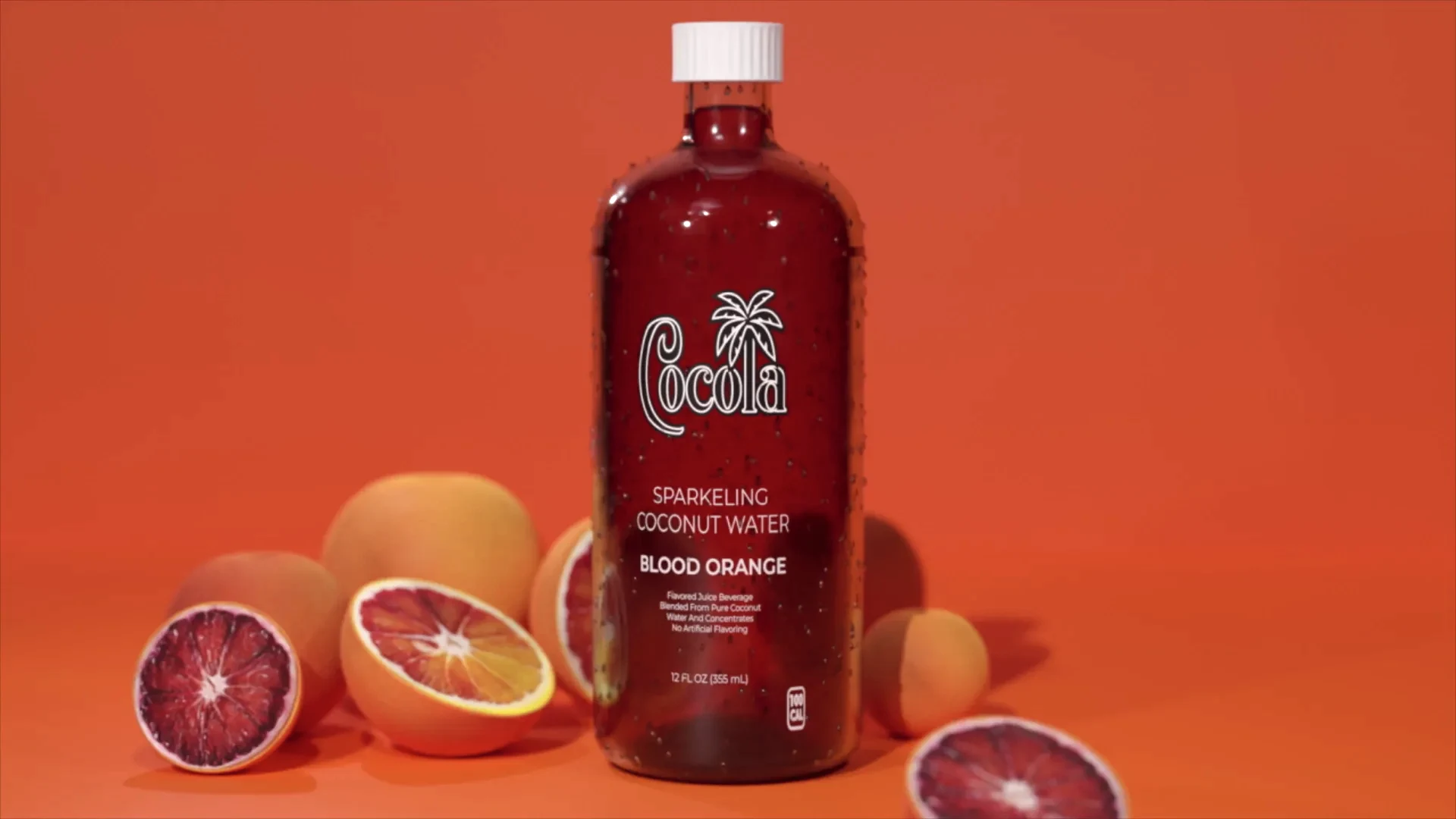 A red Cocola bottle surrounded by blood oranges
